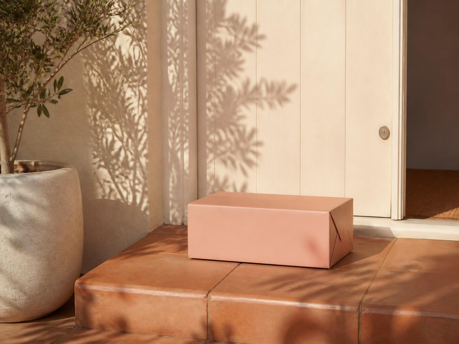 Blush pink parcel resting on a sunlit terracotta doorstep of an Australian home